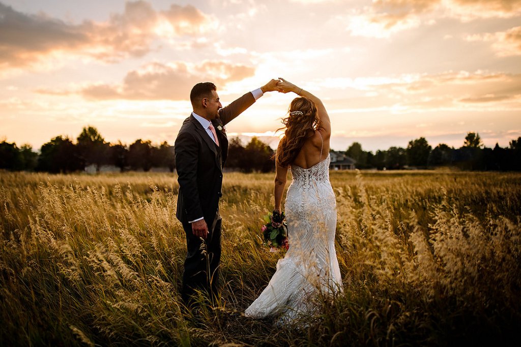 bride and groom dancing in a field