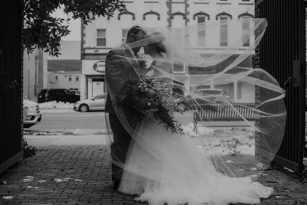 Bride and groom kissing under veil