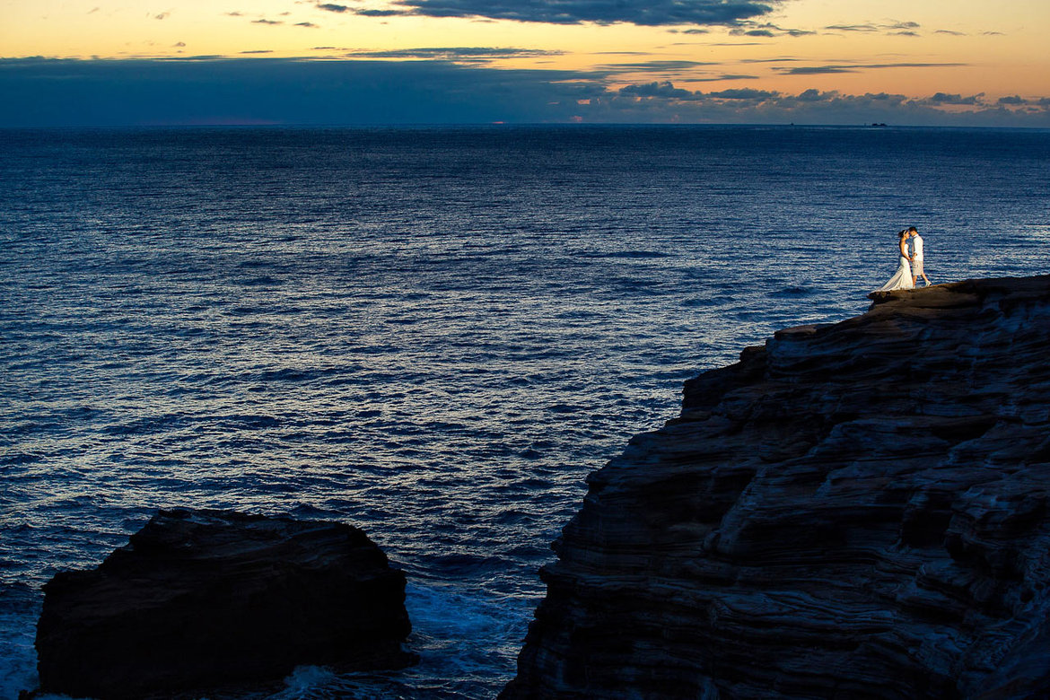 bride and groom on a cliff overlooking the ocean